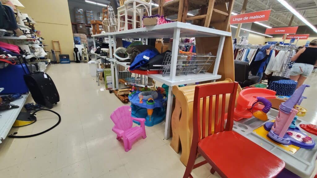 A lady shopping in a secondhand shop surrounded with shelves of baby items